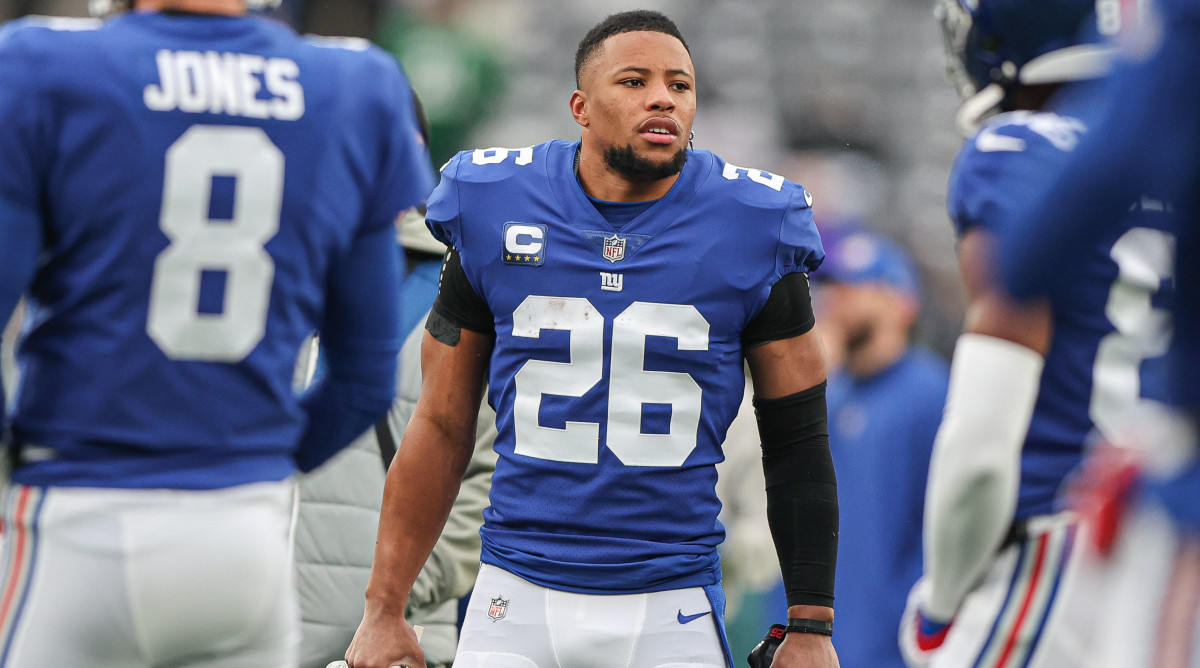 Saquon Barkely stands with his helmets off as Giants players stand around him