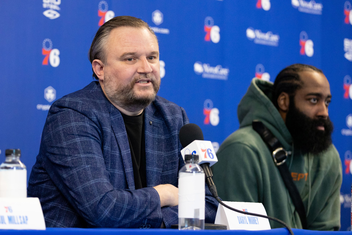 76ers president Daryl Morey speaks into a microphone while James Harden sits next to him