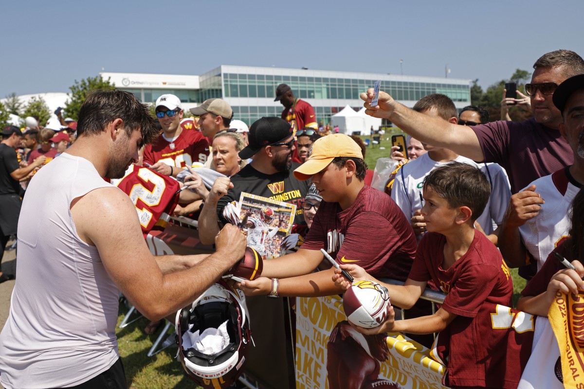 Commanders quarterback Sam Howell signs autographs for fans during training camp.