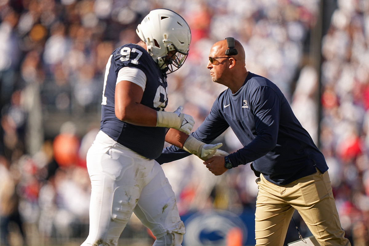 Penn State coach James Franklin high fives a player on the sidelines.