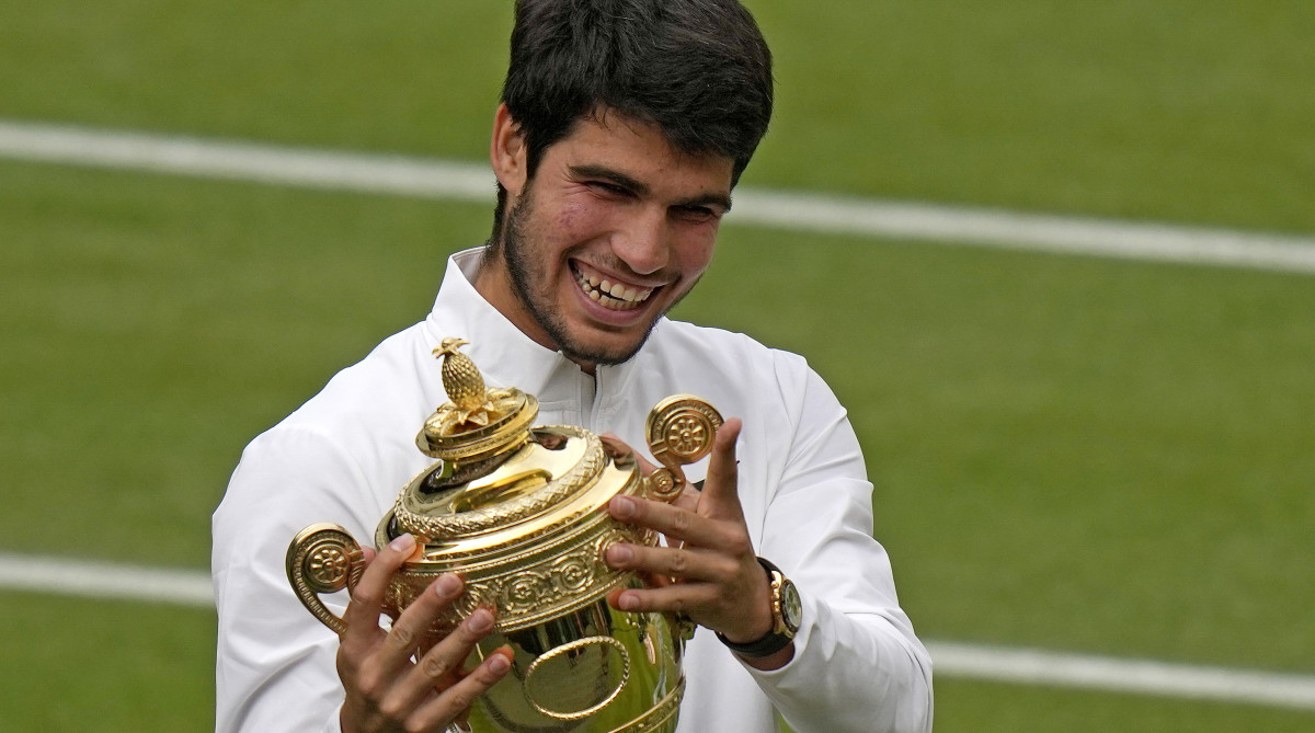 Carlos Alcaraz holds up the winner’s trophy after Wimbledon.