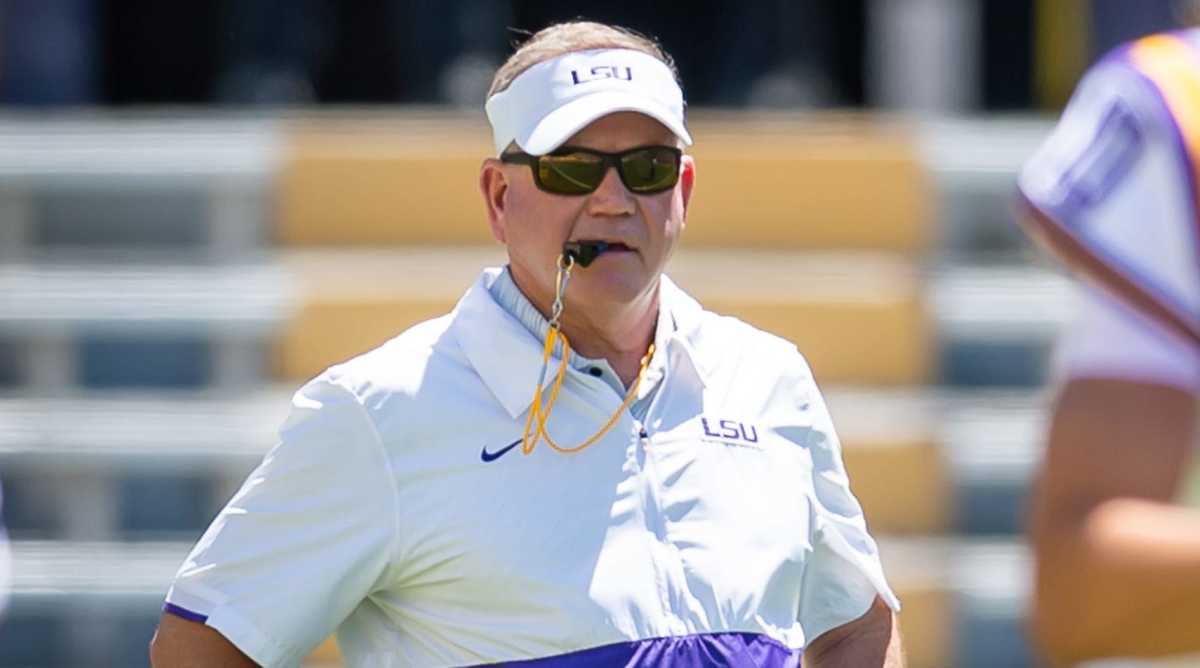 LSU coach Brian Kelly holds a whistle in his mouth at practice