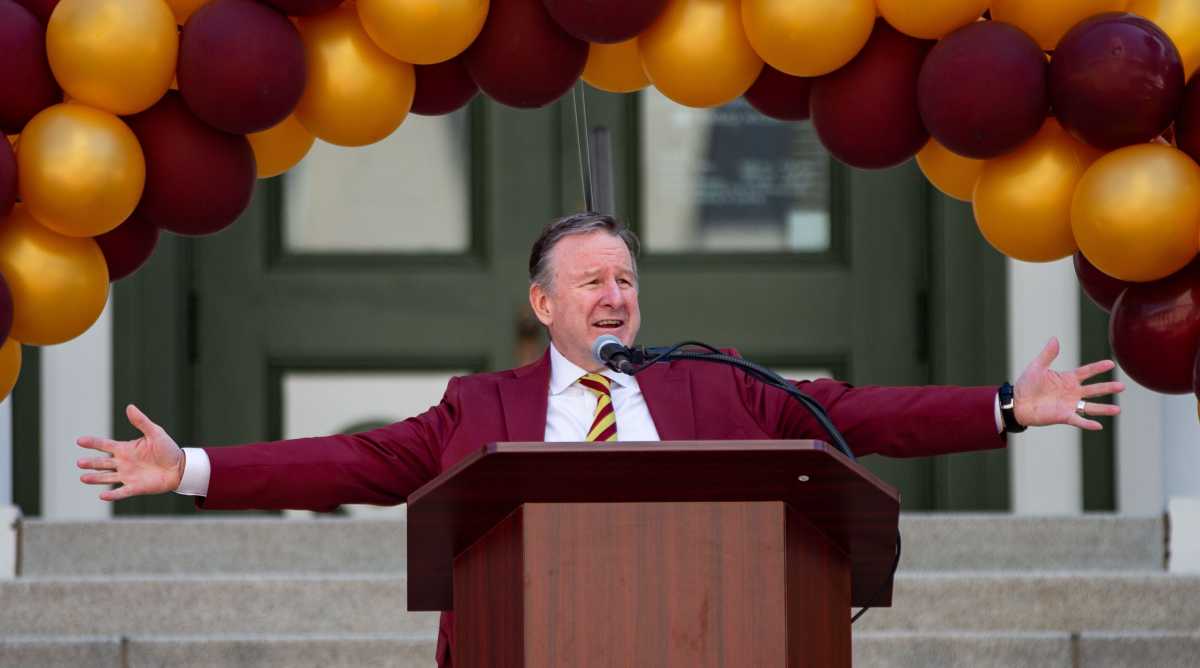 Florida State president Rick McCullough spreads his arms wide at a podium