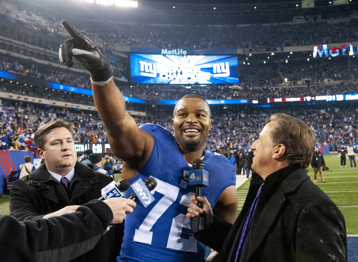 Osi Umenyiora points to the crowd while being interviewed after a Giants victory.