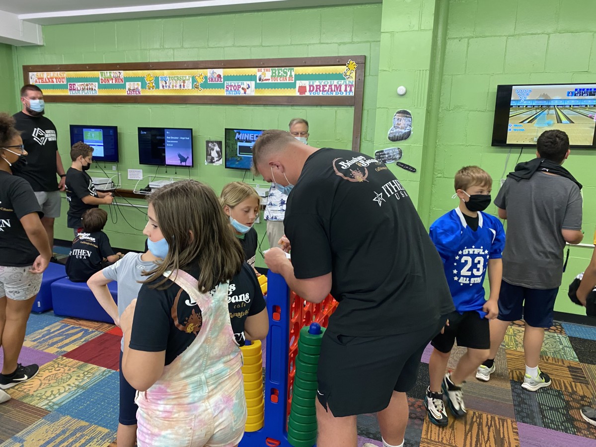 Pitt lineman Jake Kradel signs his autograph for a young fan in between games of Connect Four at the Boys and Girls Club in Millvale on Tuesday. 