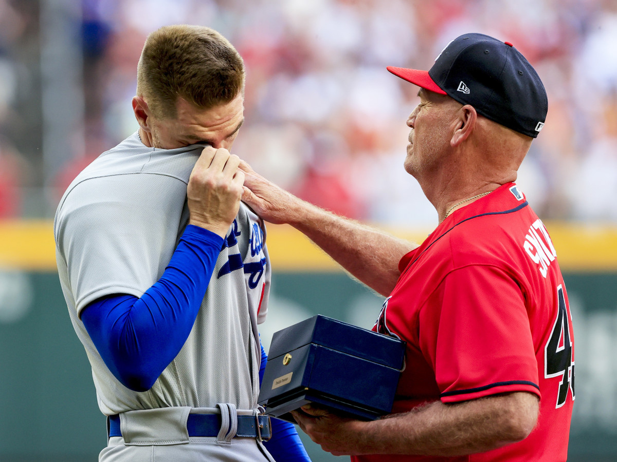 Los Angeles Dodgers first baseman Freddie Freeman, left, reacts as he is presented his World Series championship ring by Atlanta Braves manager Brian Snitker before a baseball game Friday, June 24, 2022m in Atlanta.