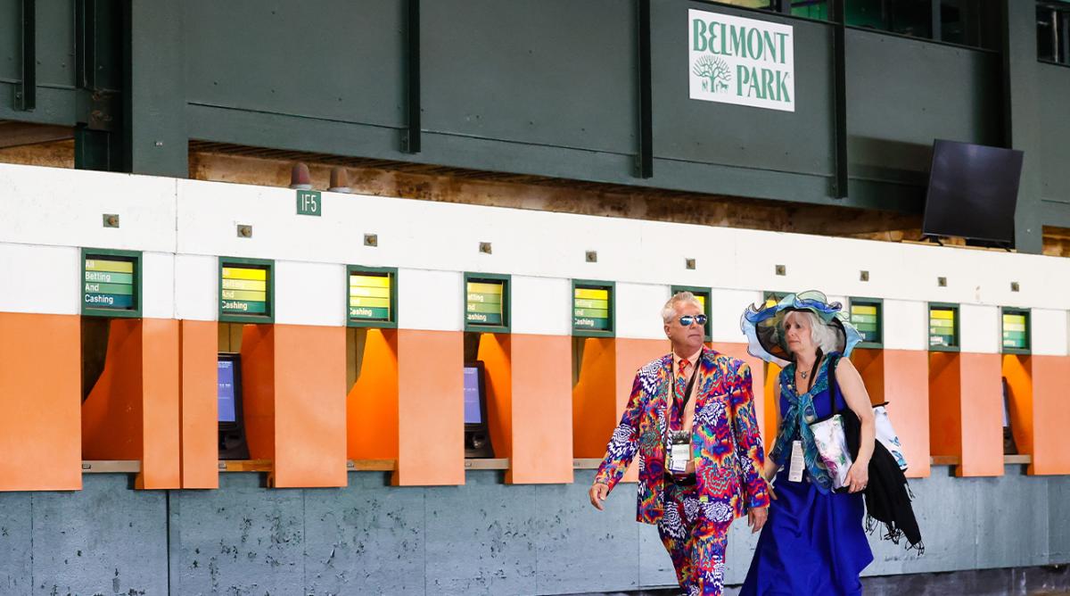 Jun 11, 2022; Elmont, NY, USA; Two horse racing fans walk by the betting station at Belmont Park Racetrack.