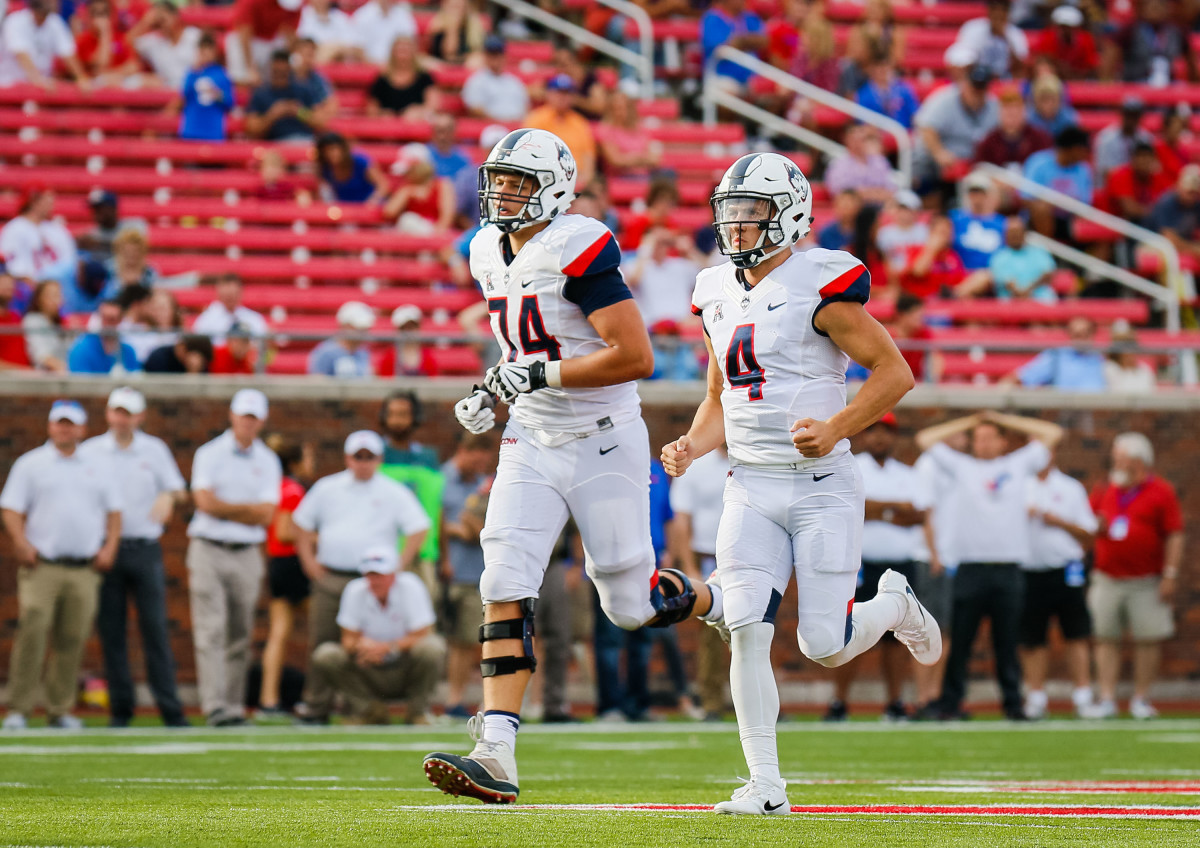 Sep 30, 2017; Dallas, TX, USA; Connecticut Huskies offensive lineman Ryan Van Demark (74) and quarterback Bryant Shirreffs (4) run downfield to celebrate a touchdown against the Southern Methodist Mustangs at Gerald J. Ford Stadium. Mandatory Credit: Ray Carlin-USA TODAY Sports