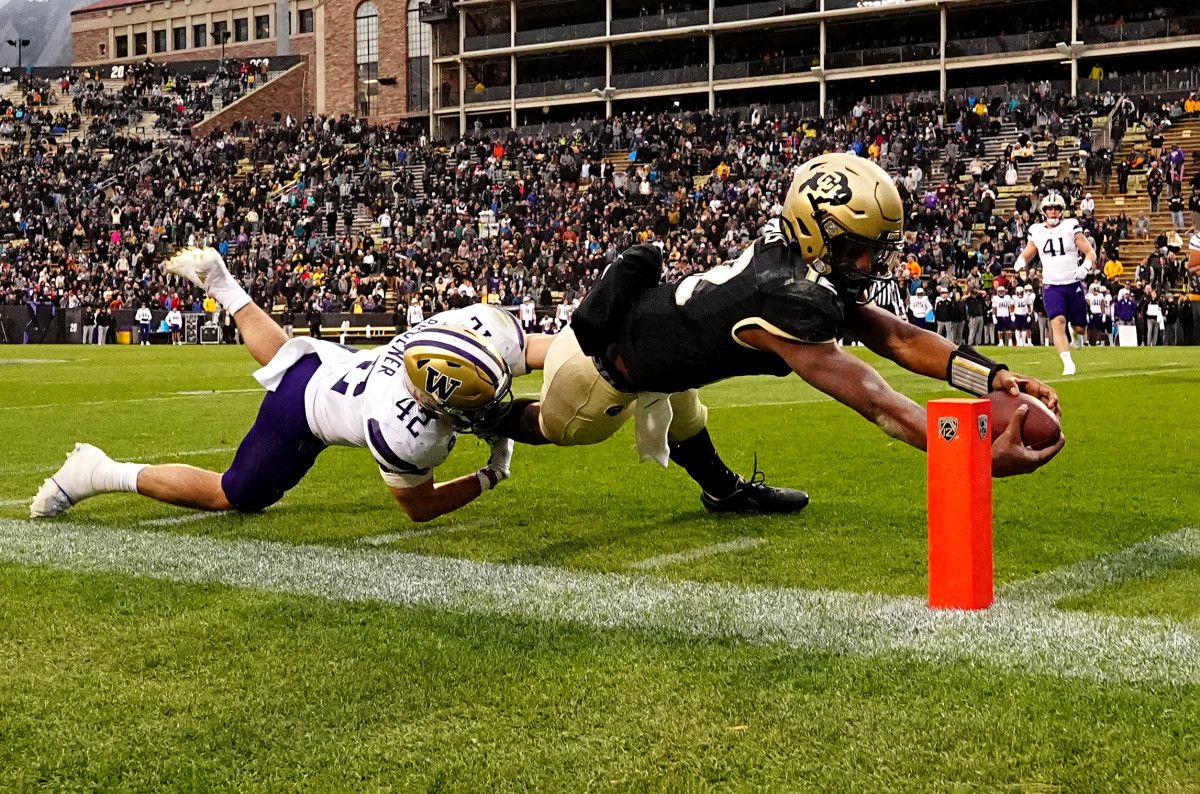 Colorado Buffaloes quarterback Brendon Lewis (12) scores a touchdown ahead of Washington Huskies linebacker Carson Bruener (42) in the fourth quarter at Folsom Field.