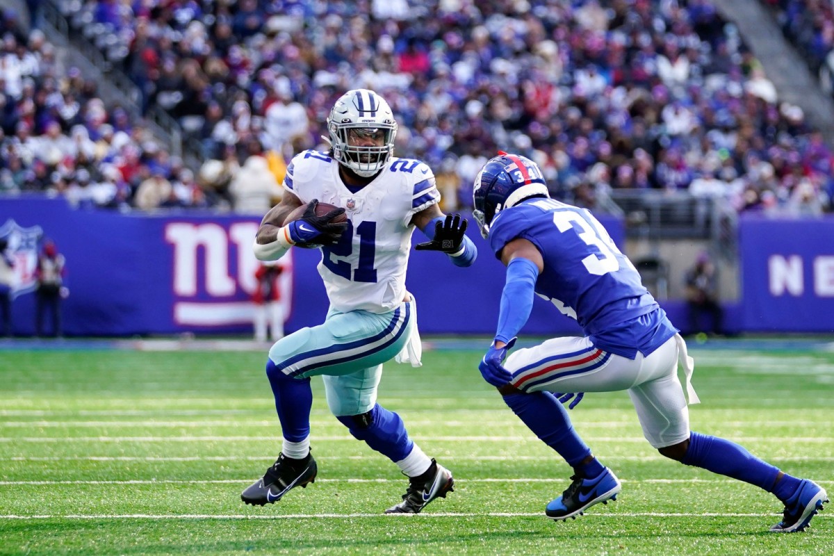 Dallas Cowboys running back Ezekiel Elliott (21) rushes with pressure from New York Giants cornerback Jarren Williams (34) in the first half at MetLife Stadium on Sunday, Dec. 19, 2021, in East Rutherford.