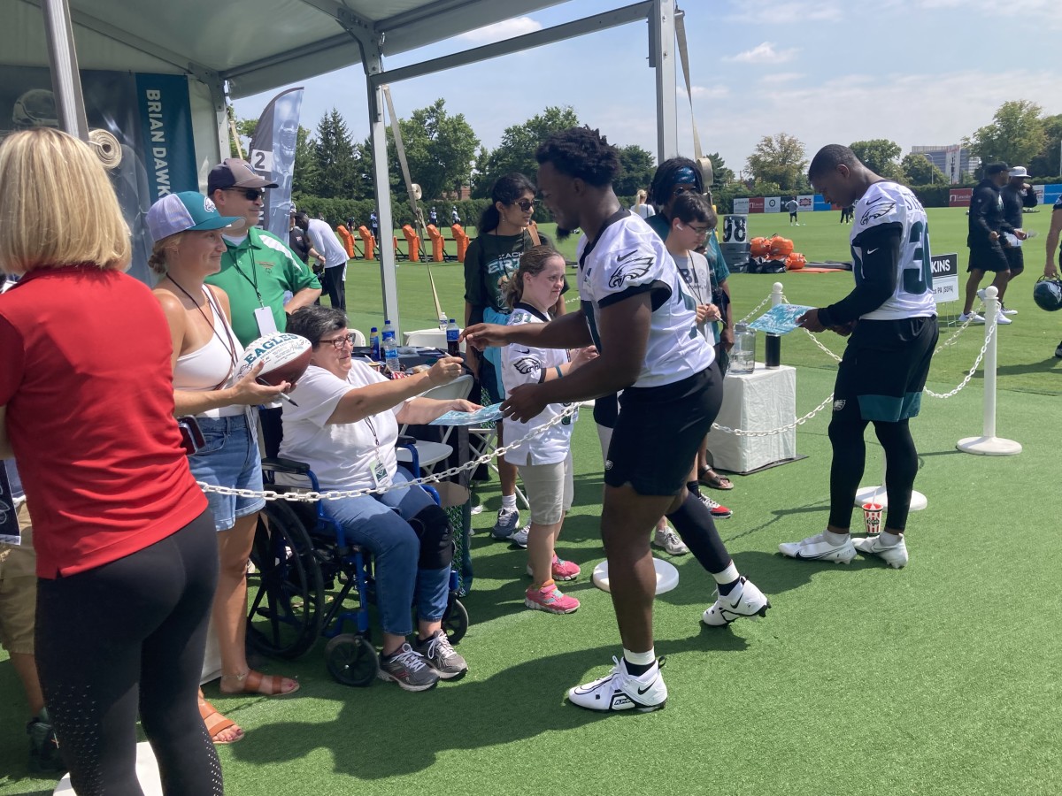 Nakobe Dean (left) and JaCoby Stevens sign autographs following the first day of Eagles training camp