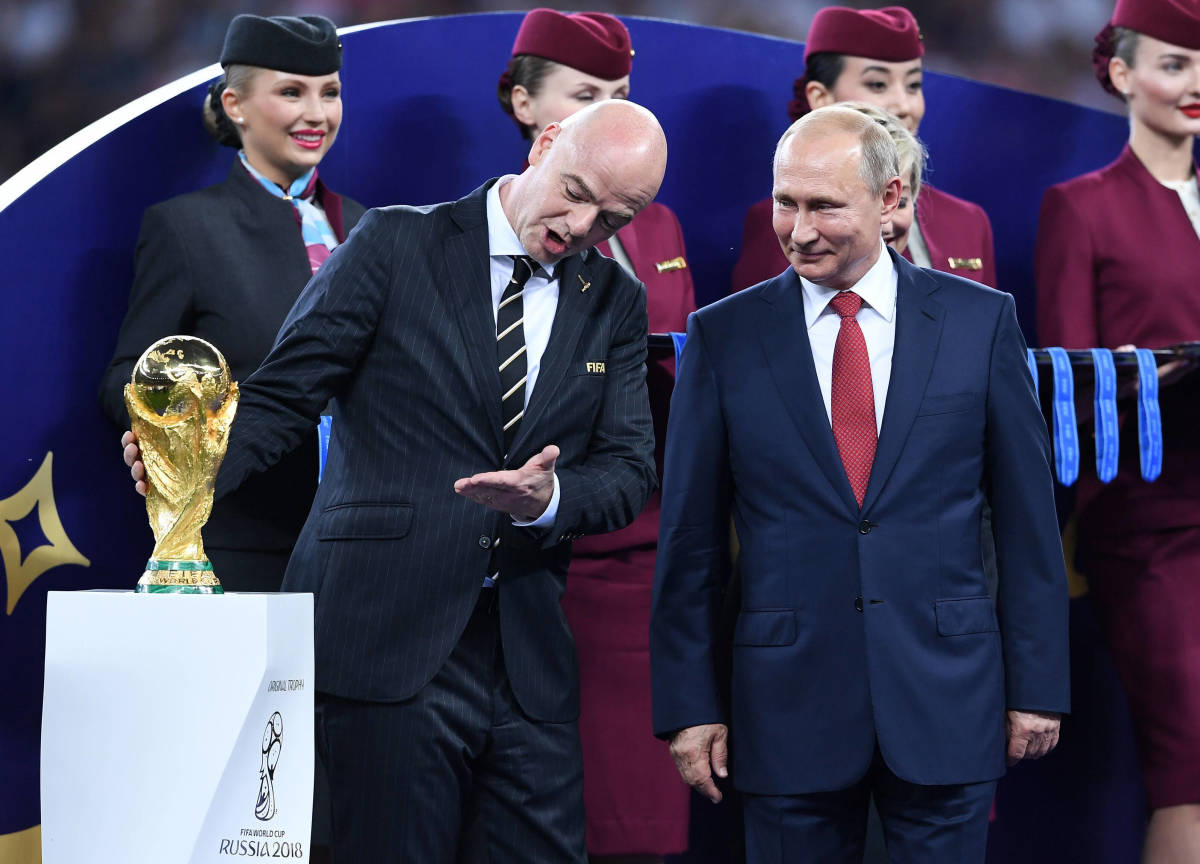 FIFA president Gianni Infantino pictured holding the World Cup trophy while talking to Vladimir Putin at Russia 2018