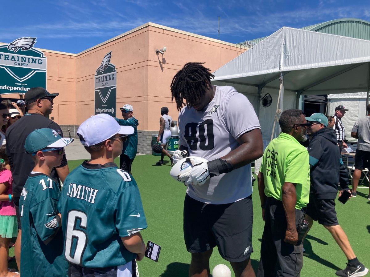 Jordan Davis signs a football for fans after practice on July 30, 2022