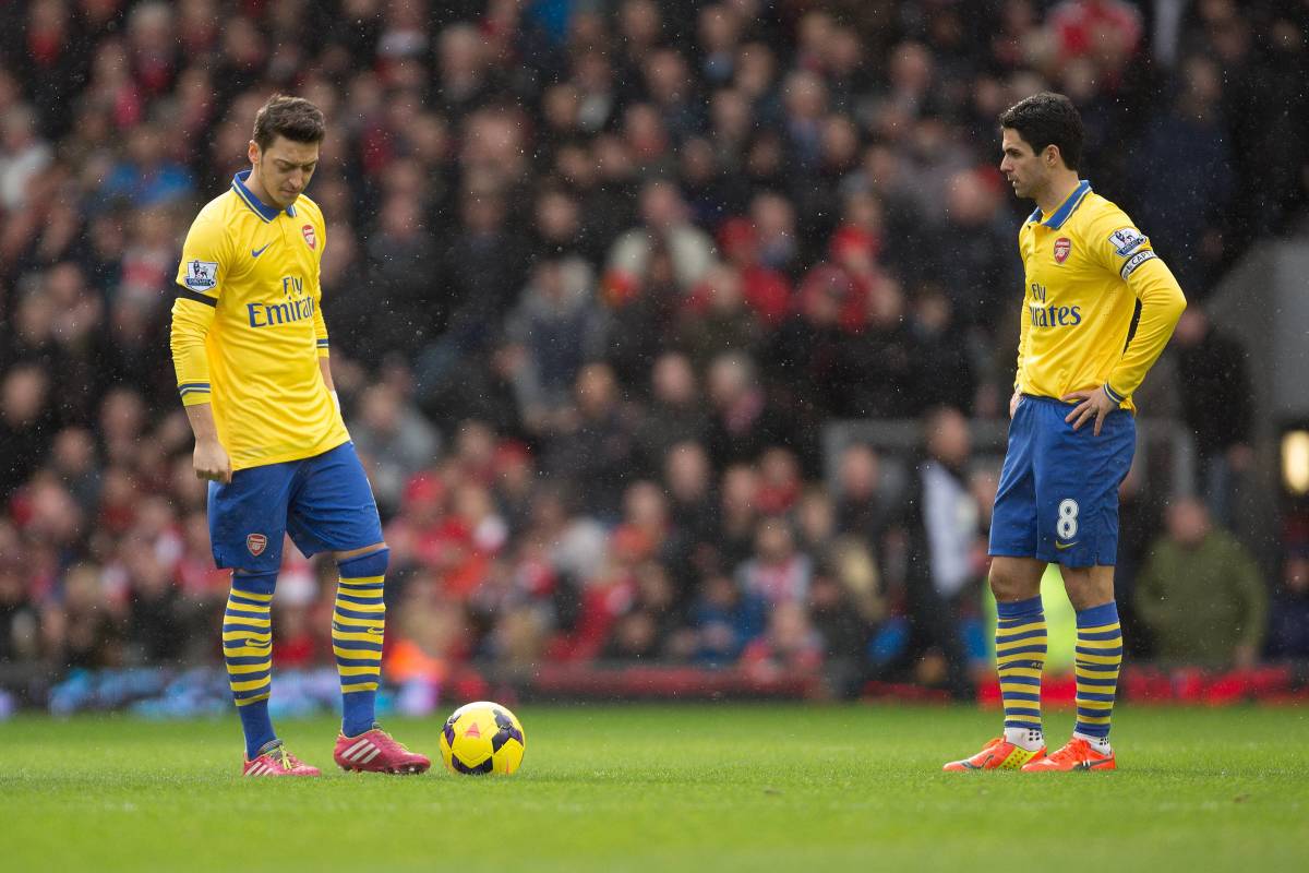 Mesut Ozil (left) and Mikel Arteta (right) pictured looking dejected during Arsenal's 5-1 loss to Liverpool at Anfield in 2014