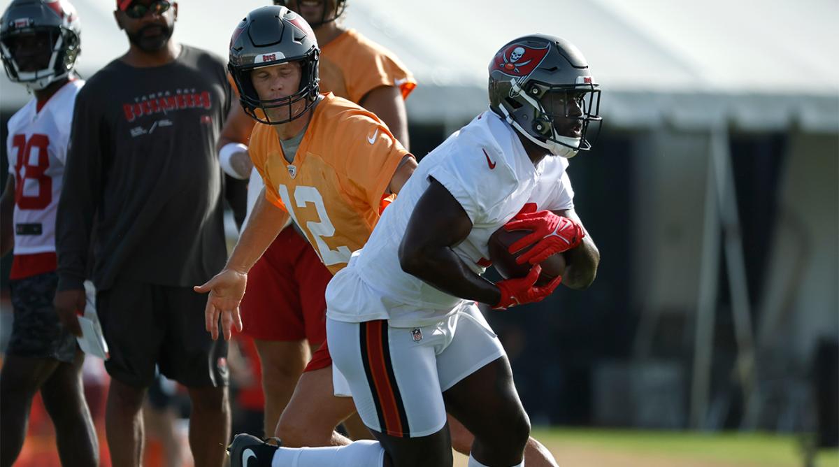 Jul 28, 2022; Tampa, FL, USA; Tampa Bay Buccaneers quarterback Tom Brady (12) hands the ball off to running back Leonard Fournette (7) at AdventHealth Training Center.