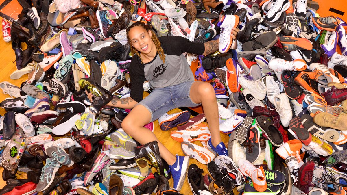WNBA player Brittney Griner sits in a pile of donated shoes.