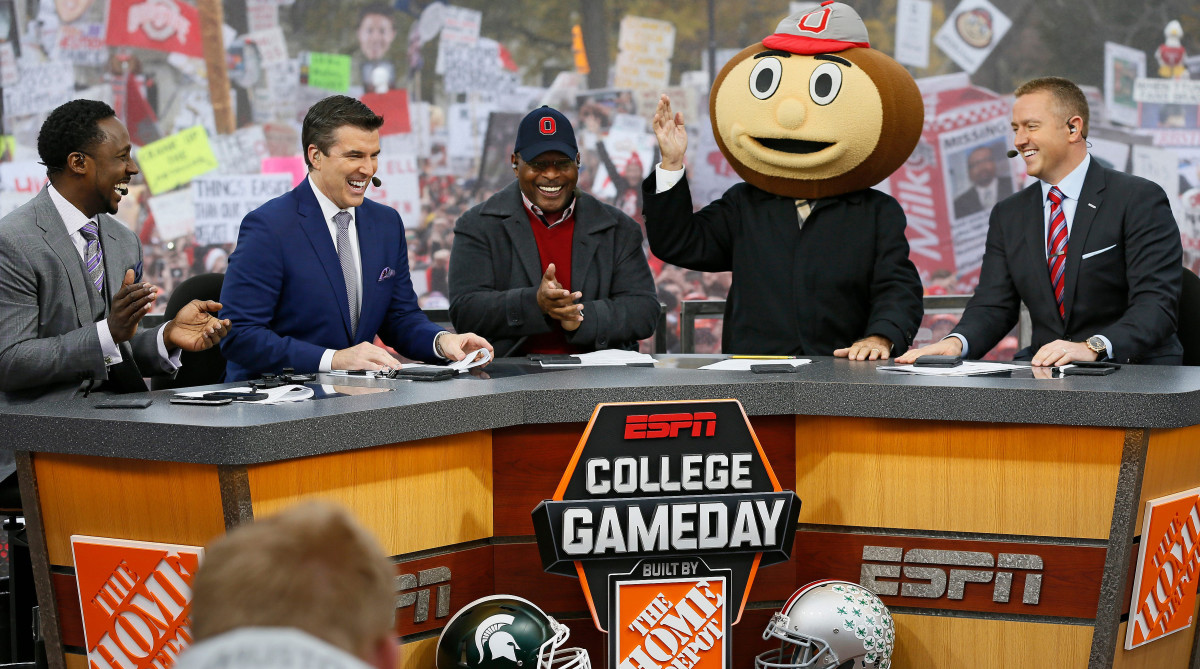 Lee Corso waves while wearing a Brutus Buckeye head at ESPN’s College Gameday.