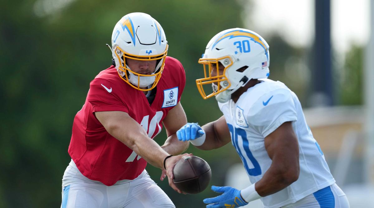 Aug 1, 2022; Costa Mesa, CA, USA; Los Angeles Chargers quarterback Justin Herbert (10) hands the ball off to running back Austin Ekeler (30) during training camp at the Jack Hammett Sports Complex.