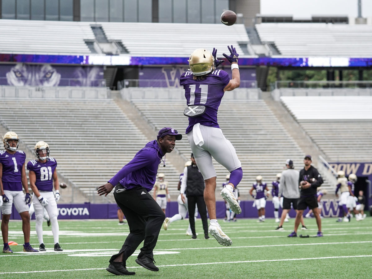 Jalen McMillan pulls in a practice pass as receivers coach JaMarcus Shephard gets up close to the action.