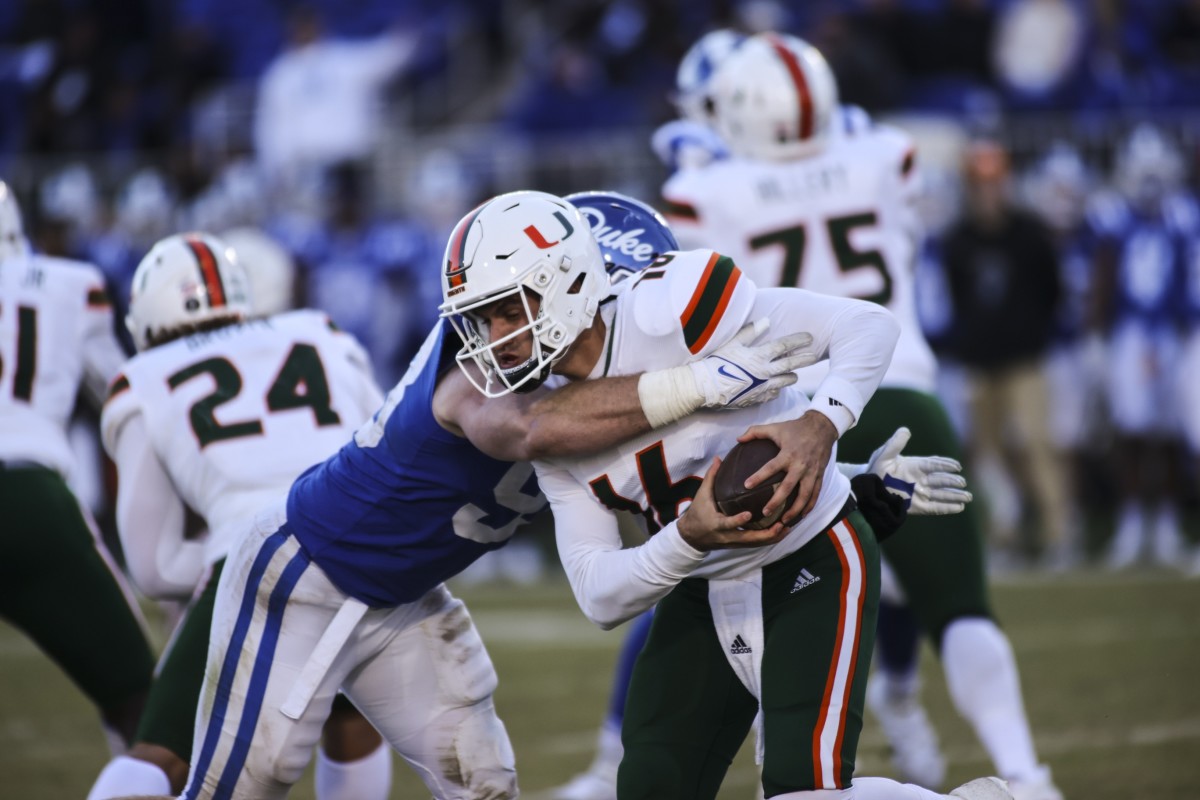 Nov 27, 2021; Durham, North Carolina, USA; Miami Hurricanes quarterback Ryan Rizk (16) with the football taken down by Duke Blue Devils defensive end Ben Frye (93) during the second half of the game against the Miami Hurricanes at Wallace Wade Stadium. at Wallace Wade Stadium. Mandatory Credit: Jaylynn Nash-USA TODAY Sports