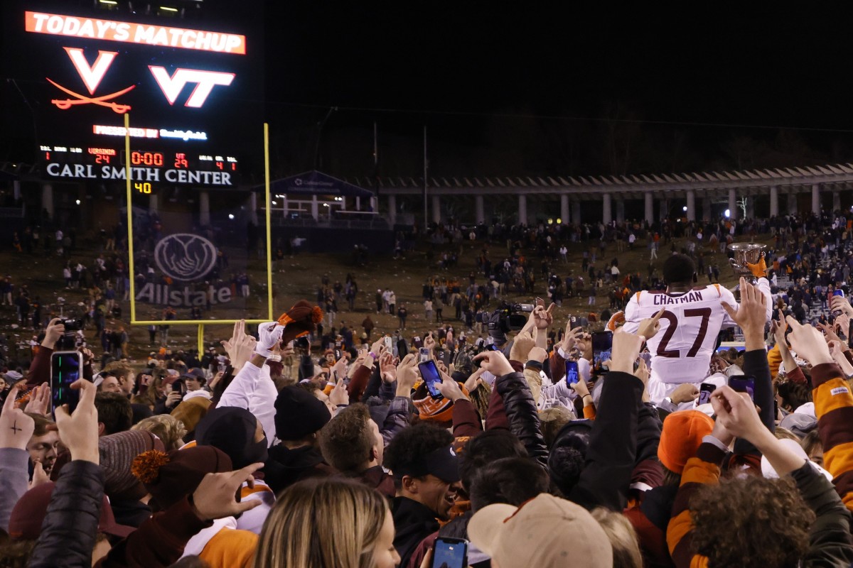 Virginia Tech Hokies defensive back Armani Chatman (27) celebrates with teammates and fans while holding the Commonwealth Cup after the Hokies' game against the Virginia Cavaliers at Scott Stadium.