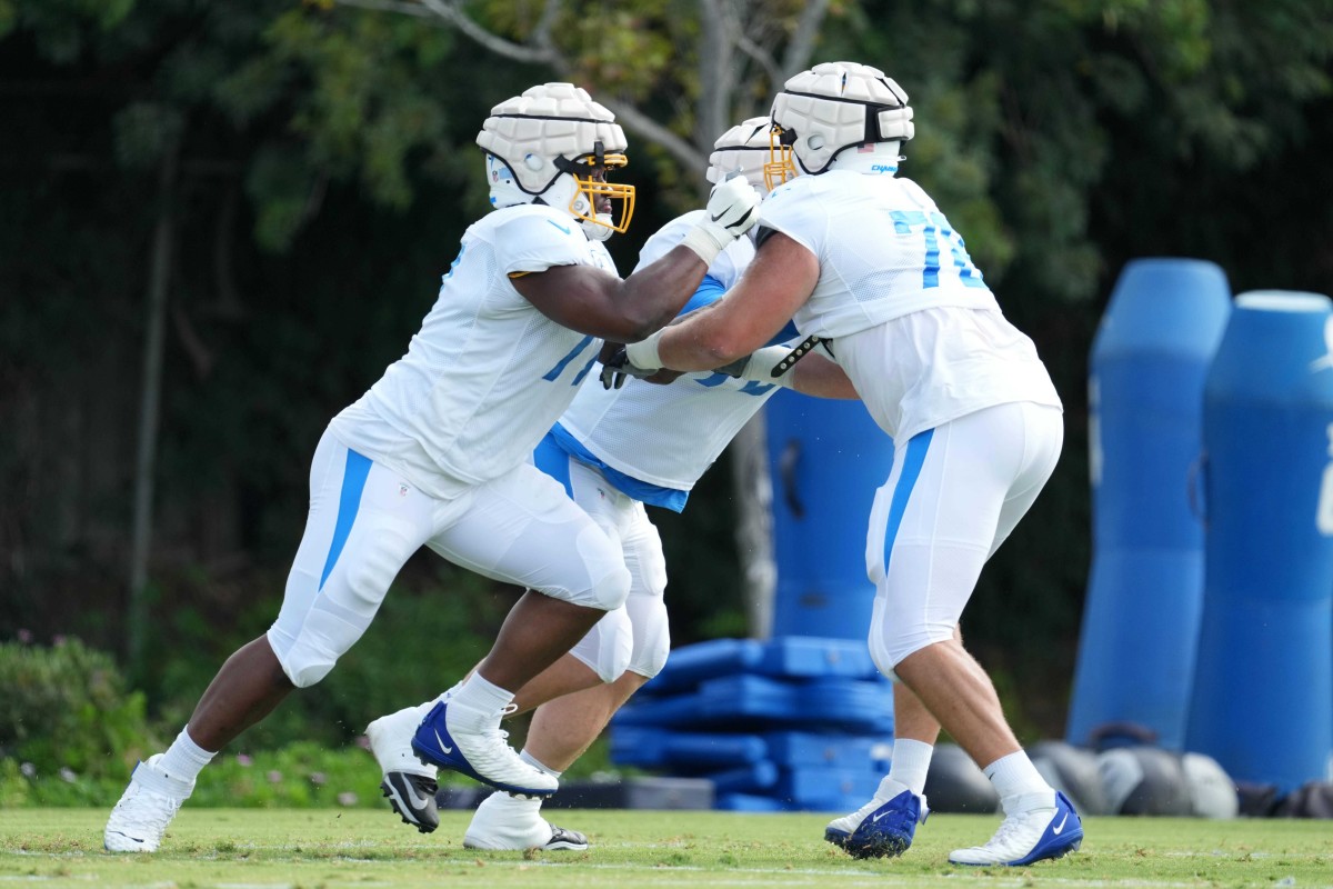 Aug 1, 2022; Costa Mesa, CA, USA; Los Angeles Chargers guard Zion Johnson (77) and tackle Zack Bailey (78) participate in drills wearing Guardian helmet protective cover caps during training camp at the Jack Hammett Sports Complex. Mandatory Credit: Kirby Lee-USA TODAY Sports