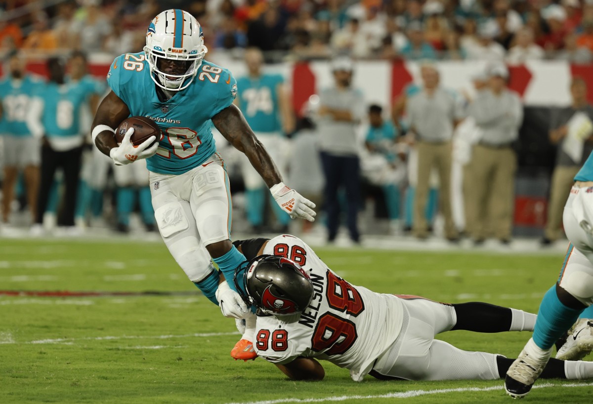 Aug 13, 2022; Tampa, Florida, USA; Miami Dolphins running back Salvon Ahmed (26) runs with the ball as Tampa Bay Buccaneers linebacker Anthony Nelson (98) tackles during the second quarter at Raymond James Stadium. Mandatory Credit: Kim Klement-USA TODAY Sports