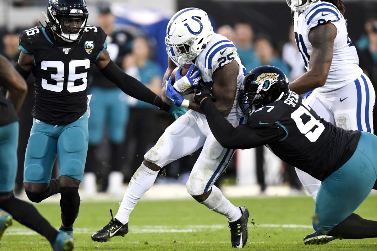 Dec 29, 2019; Jacksonville, Florida, USA; Indianapolis Colts running back Marlon Mack (25) runs the ball as Jacksonville Jaguars defensive tackle Akeem Spence (97) defends during the second quarter at TIAA Bank Field. Mandatory Credit: Douglas DeFelice-USA TODAY Sports