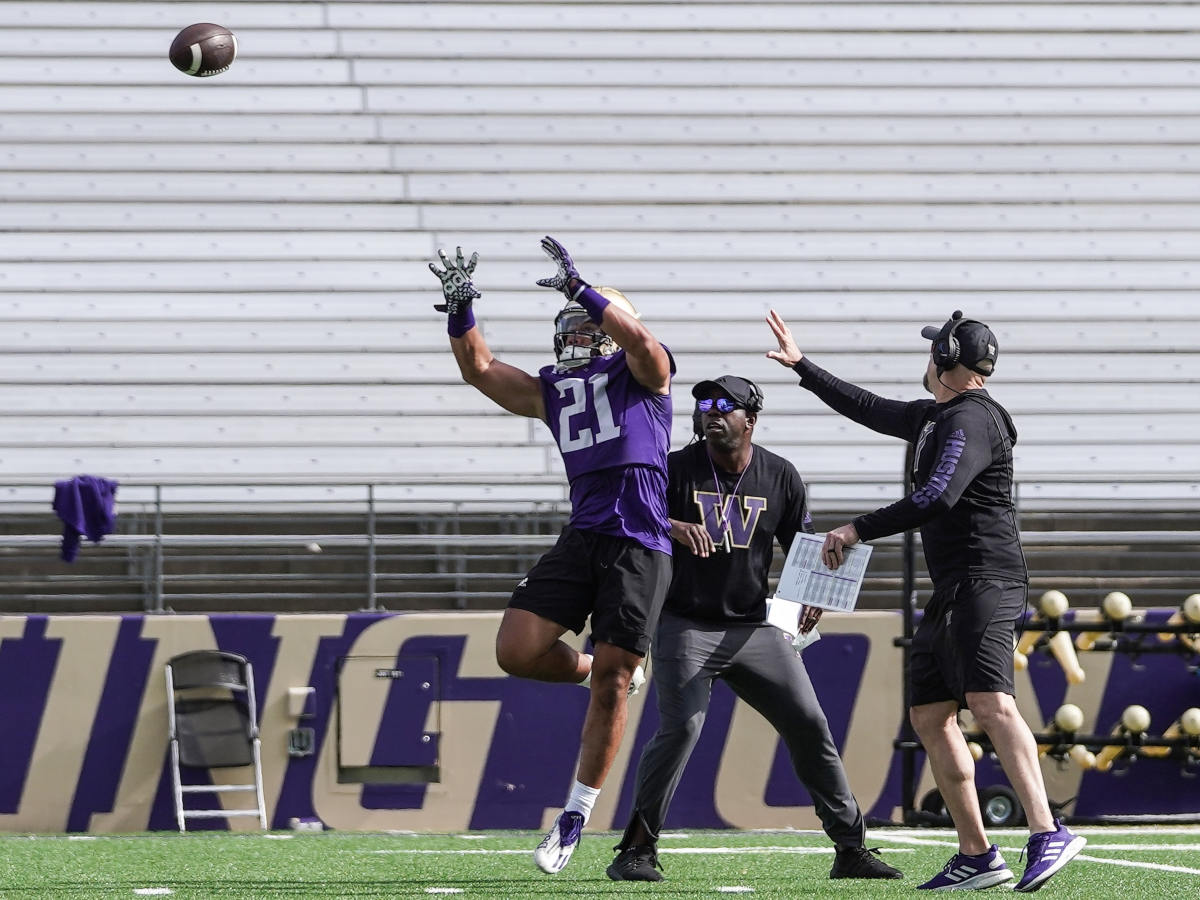 Running back Wayne Taulapapa makes a catch with receivers coach JaMarcus Shephard right behind him.