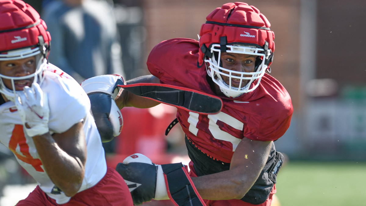 Arkansas Razorbacks defensive back Simeon Blair wears boxing gloves while covering Warren Thompson in Thursday morning's practice on the grass outdoor field at the football center in Fayetteville, Arkansas.