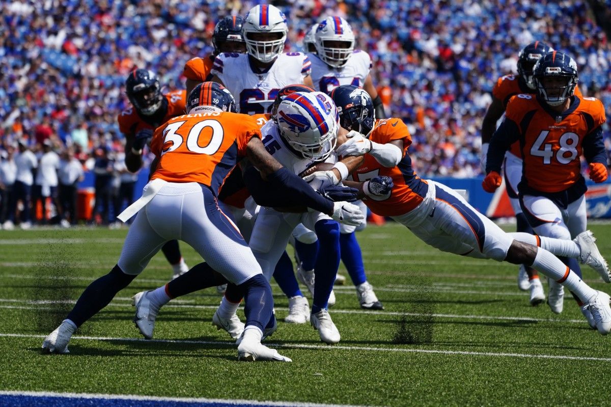 Denver Broncos safety Caden Sterns (30) and Denver Broncos cornerback Michael Ojemudia (13) tackle Buffalo Bills wide receiver Jake Kumerow (15) short of the end zone during the first half at Highmark Stadium.