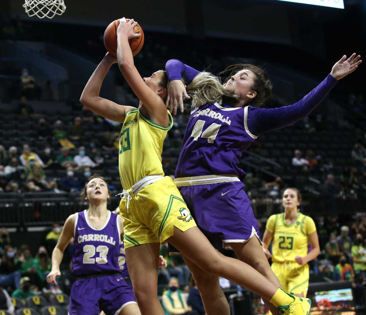 Sydney Parrish is fouled by Carroll College's Maddie Geritz as she goes up for a shot during the second half in Eugene Jan. 2, 2022.