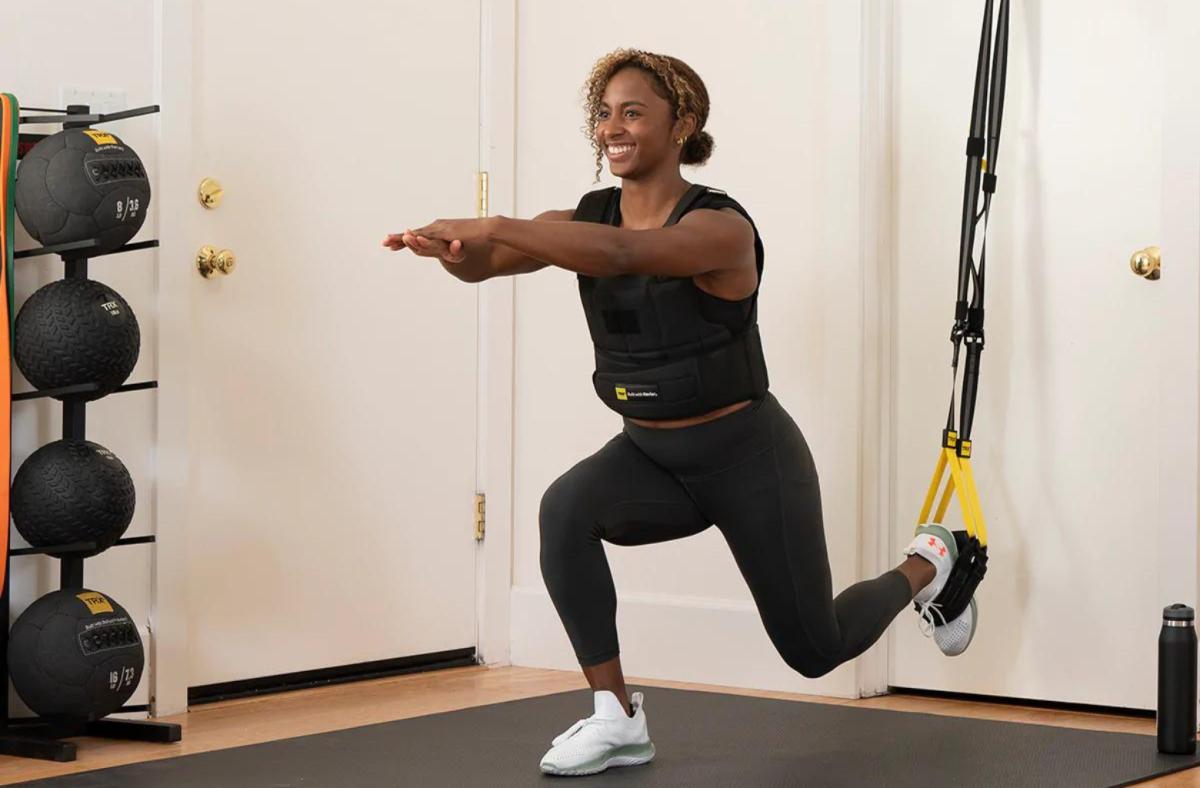 A woman using the TRX straps to perform a single leg squat