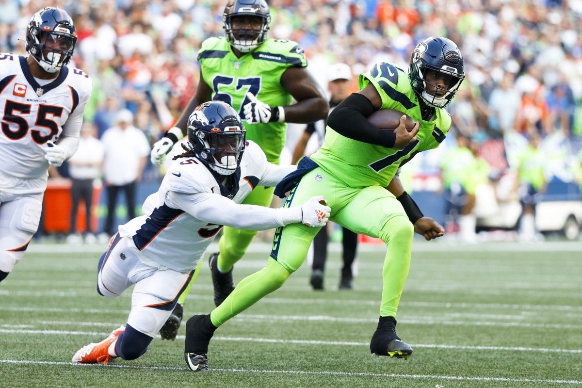 Seattle Seahawks quarterback Geno Smith (7) breaks a tackle attempt by Denver Broncos linebacker Randy Gregory (5) during the second quarter at Lumen Field.