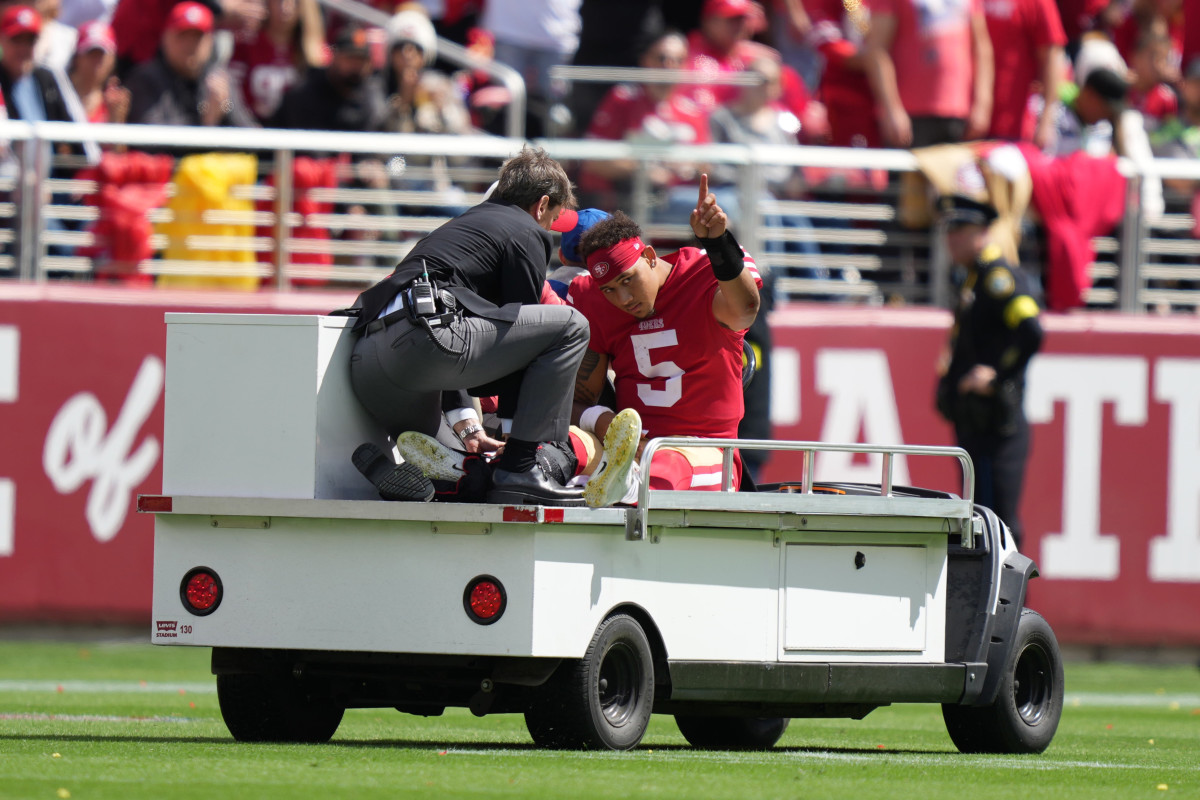 Trey Lance gestures to the crowd as he's carted off after an ankle injury
