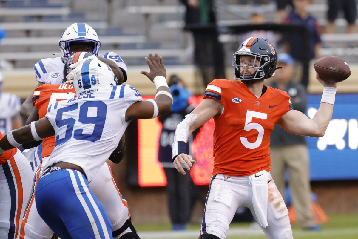 Virginia Cavaliers quarterback Brennan Armstrong (5) passes the ball under pressure from Duke Blue Devils defensive end Michael Reese (59) during the second quarter at Scott Stadium.