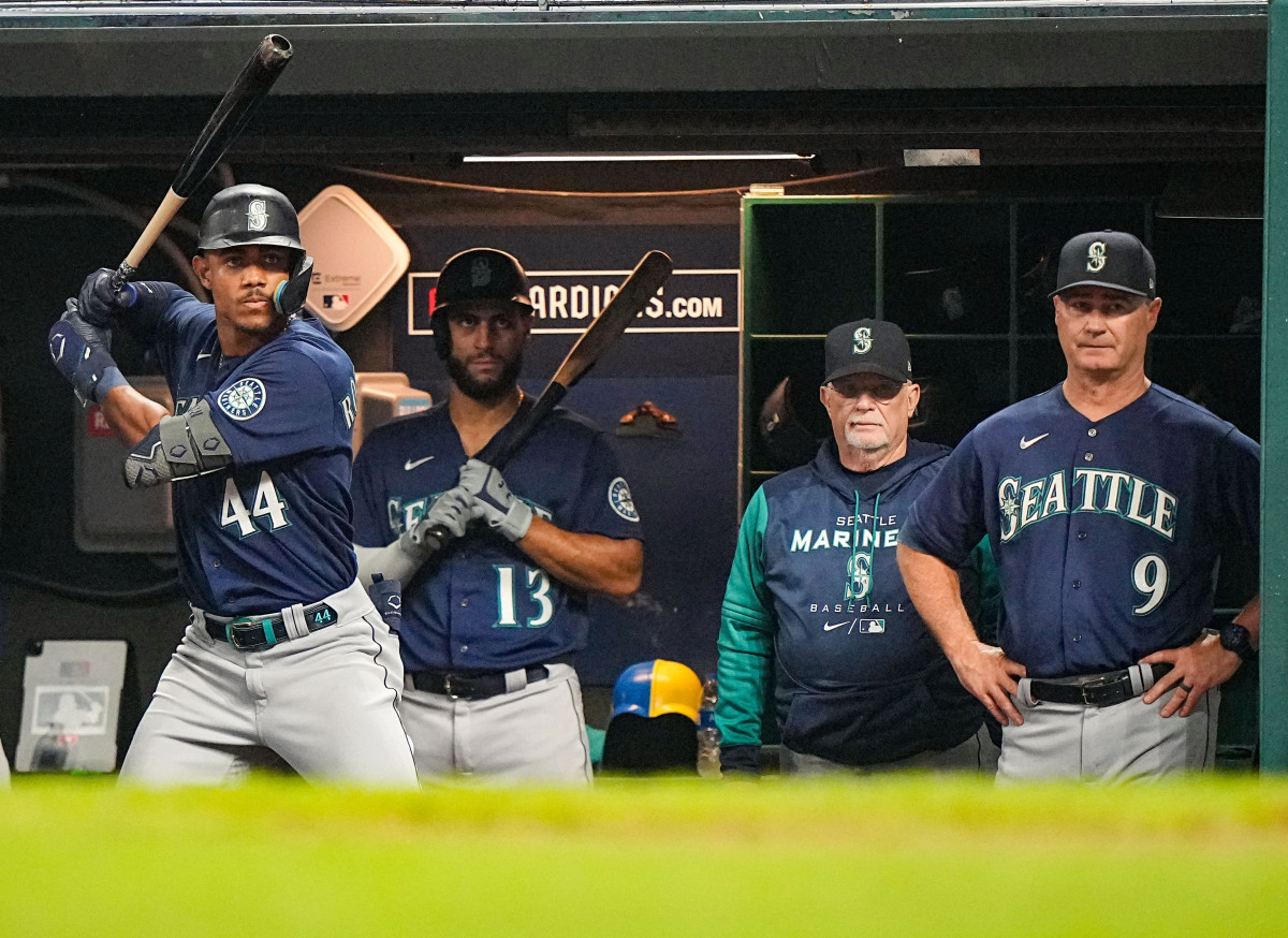 Julio Rodríguez prepares to hit in the dugout as manager Scott Servais (9) looks on.