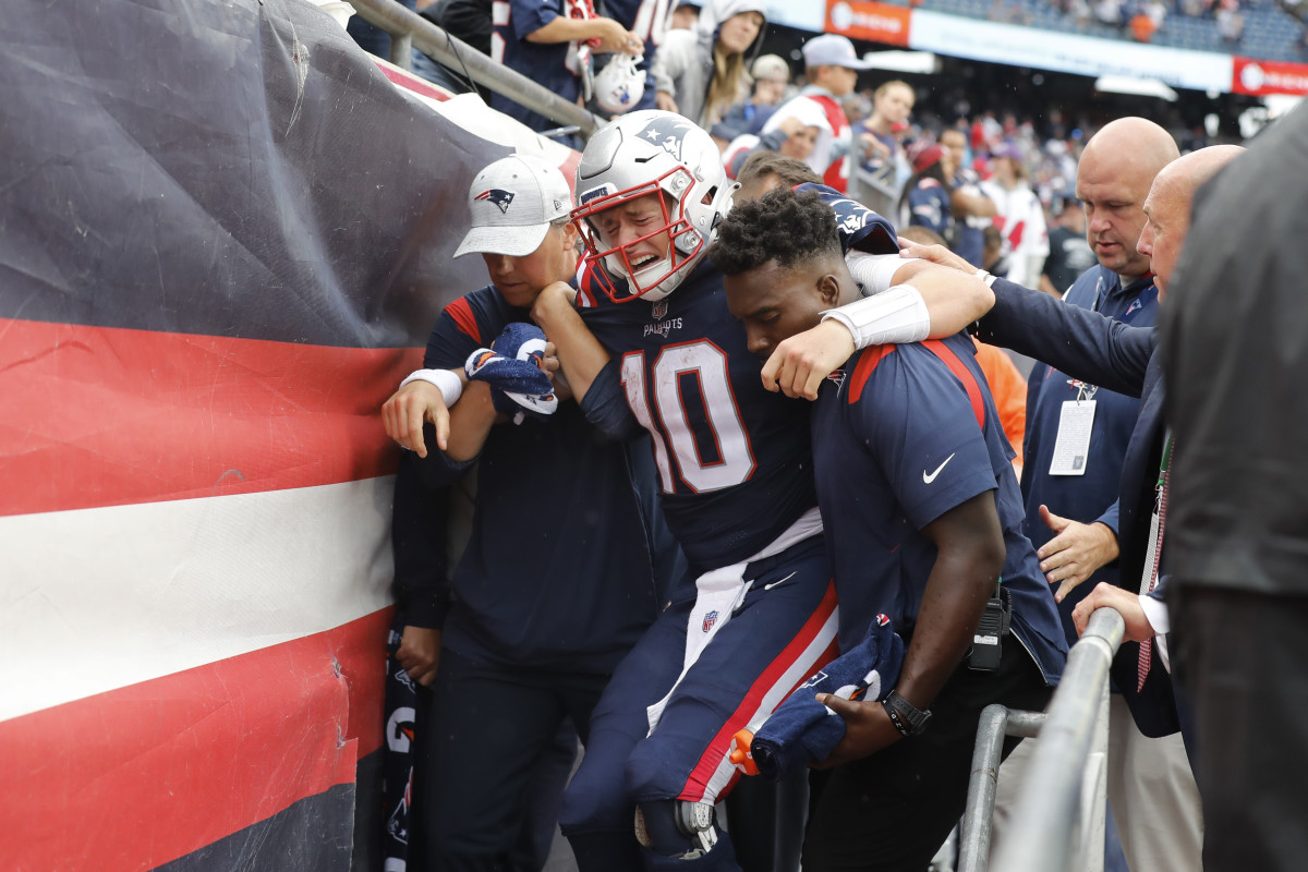 New England Patriots quarterback Mac Jones (10) is helped off the field after suffering a leg injury with less than two minutes to play in the second half of an NFL football game against the Baltimore Ravens, Sunday, Sept. 25, 2022, in Foxborough, Mass.