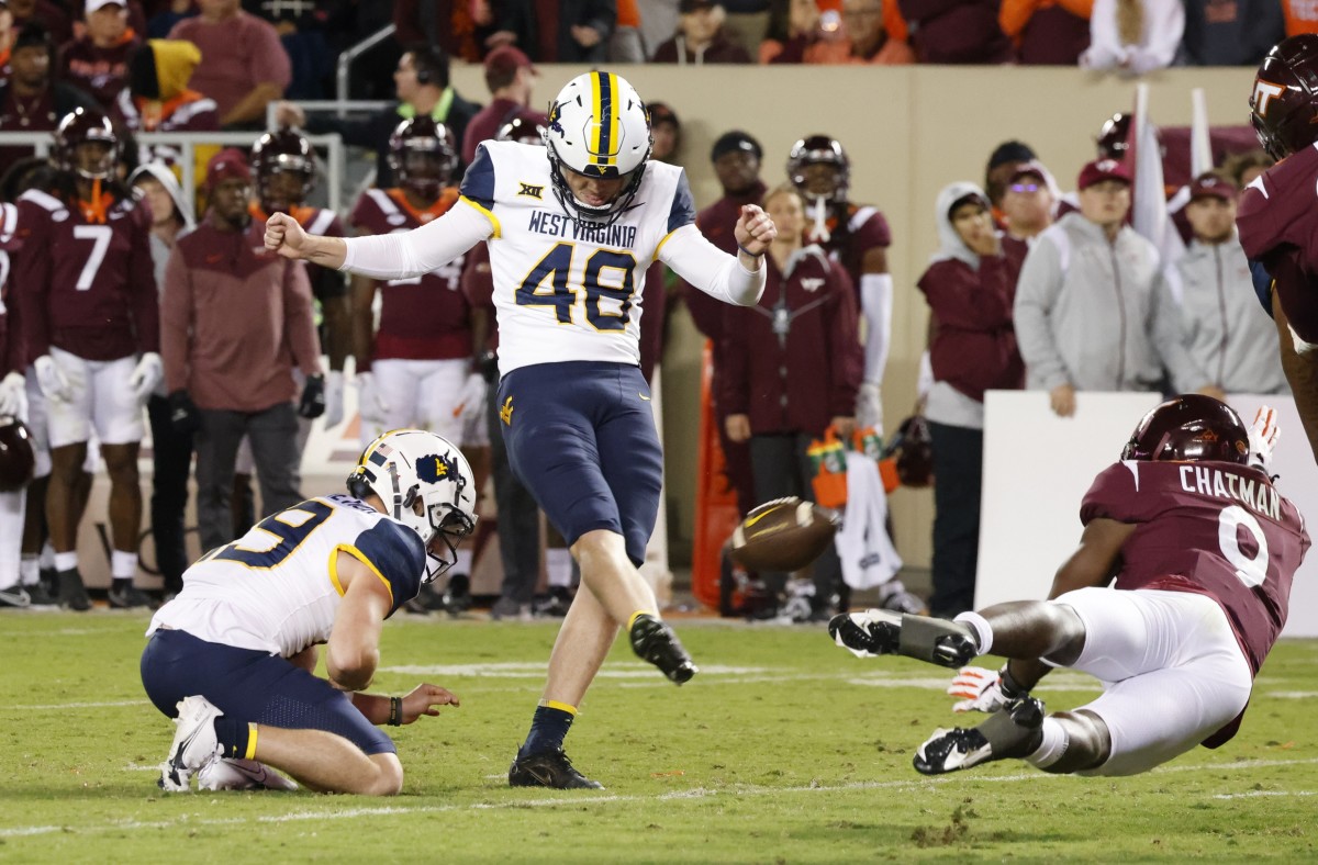 Sep 22, 2022; Blacksburg, Virginia, USA; West Virginia Mountaineers place kicker Casey Legg (48) kicks a field goal from the hold of place kicker Danny King (39) as Virginia Tech Hokies defensive back Armani Chatman (9) tries to block during the second half at Lane Stadium.