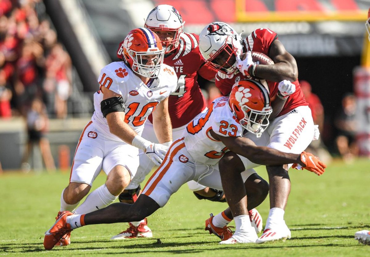 Clemson linebacker Baylon Spector (10) and cornerback Andrew Booth Jr. (23) tackle N.C. State running back Zonovan Knight (7)
