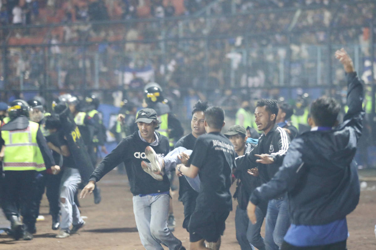 A group of men pictured desperately carrying an injured person during the 2022 Kanjuruhan Stadium disaster