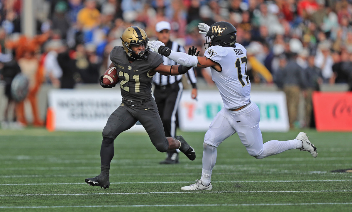 Army running back Tyrell Robinson carries the ball while former  defensive back Traveon Redd hunts him down