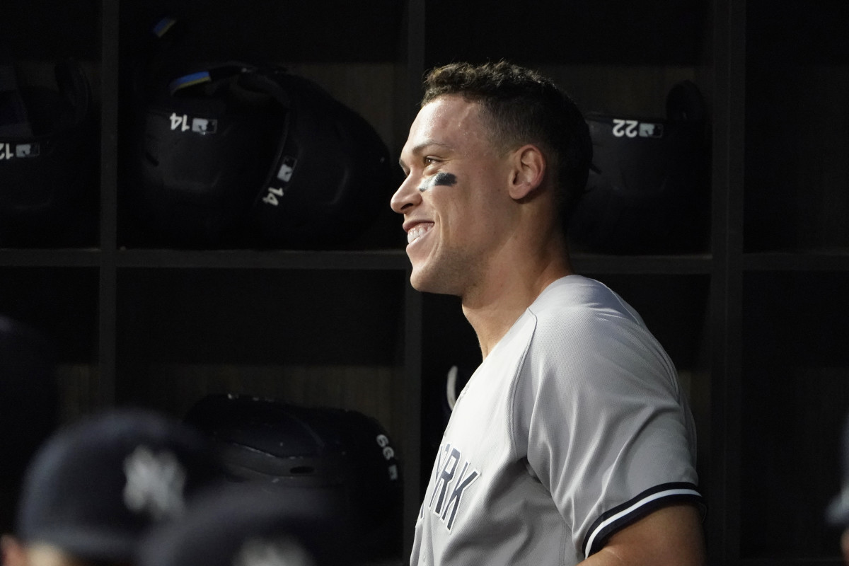New York Yankees’ Aaron Judge smiles in the dugout after hitting a solo home run, his 62nd of the season, during the first inning in the second baseball game of a doubleheader against the Texas Rangers in Arlington, Texas, Tuesday, Oct. 4, 2022. With the home run, Judge set the AL record for home runs in a season, passing Roger Maris.
