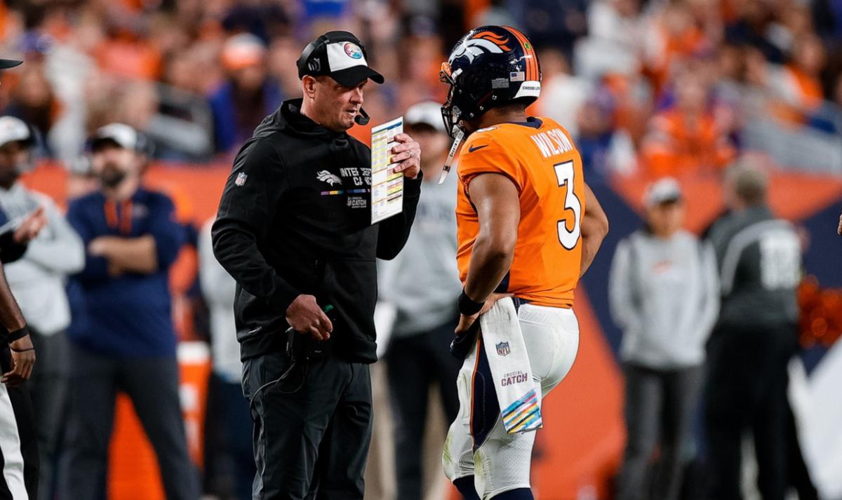Denver Broncos head coach Nathaniel Hackett talks with quarterback Russell Wilson (3) as side judge Anthony Jeffries (36) and down judge Kent Payne (79) look on in the fourth quarter against the Indianapolis Colts at Empower Field at Mile High.