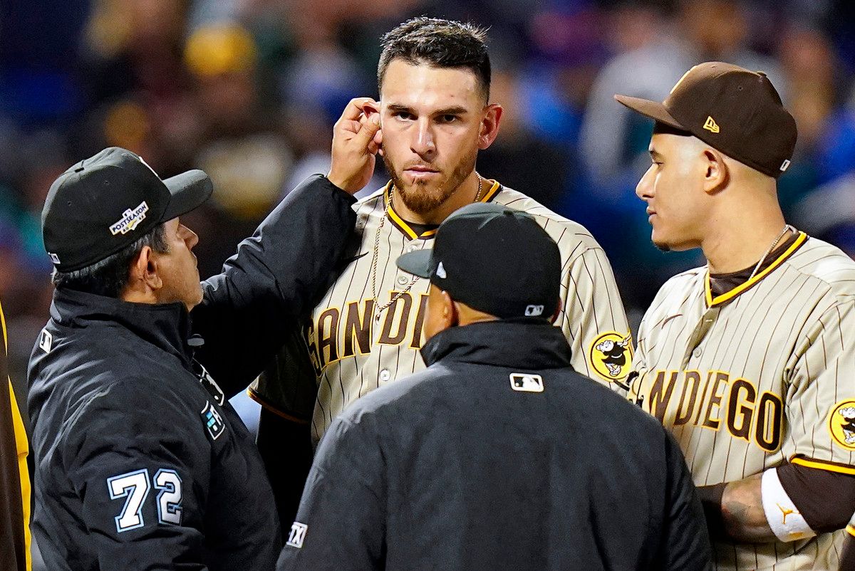 Umpire Alfonso Márquez checks for substances behind the ears of Padres pitcher Joe Musgrove.