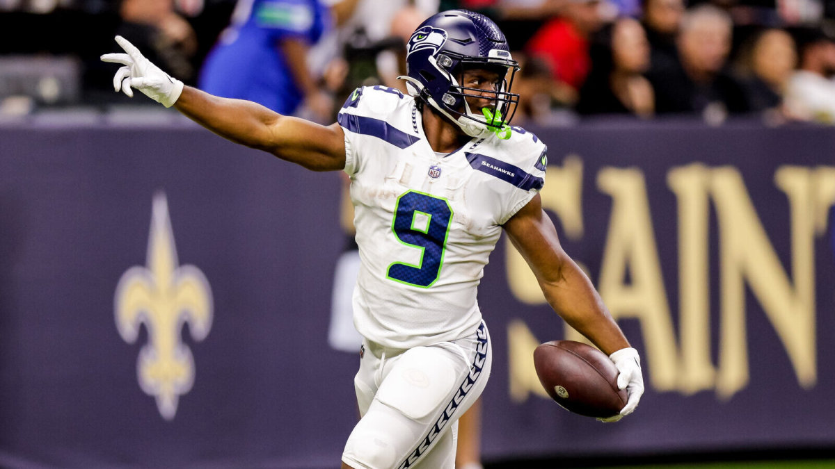 Seattle Seahawks Kenneth Walker III runs with one arm up in the air and one holding the ball