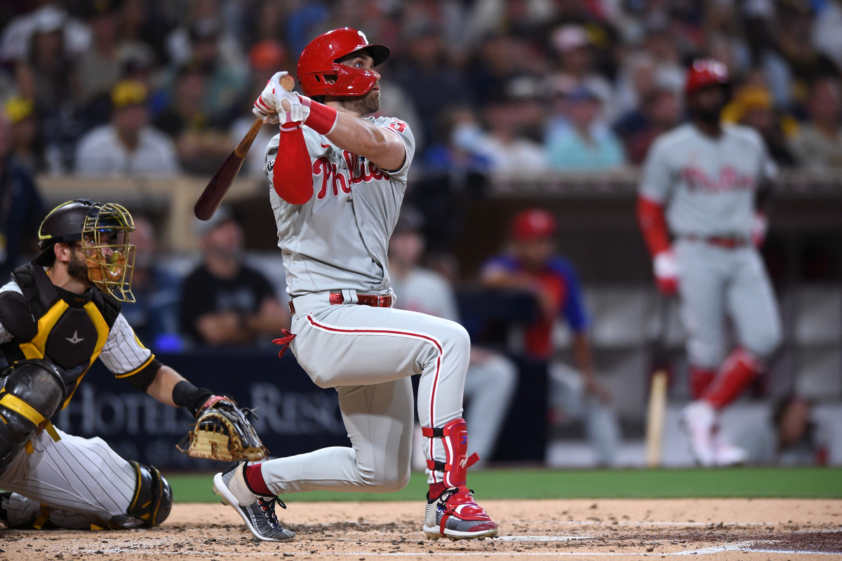 Phillies star Bryce Harper swings in front of a Padres catcher