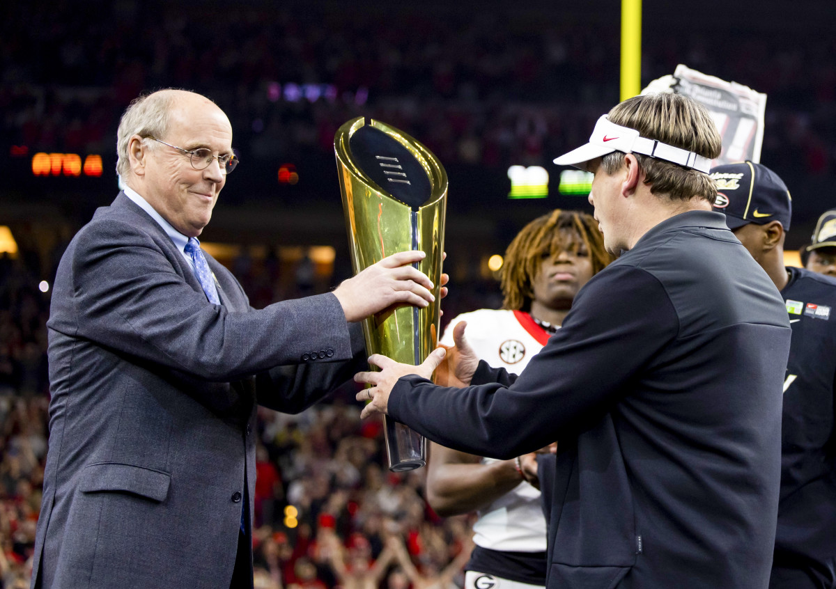 Bill Hancock hands the CFP trophy to Georgia coach Kirby Smart.