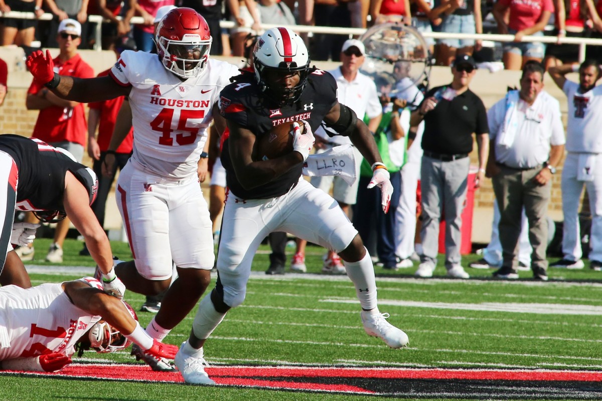 Sep 10, 2022; Lubbock, Texas, USA; Texas Tech Red Raiders running back SaRodorick Thompson (4) rushes against Houston Cougars defensive end Nadame Tucker (45) in the first half at Jones AT&T Stadium and Cody Campbell Field.
