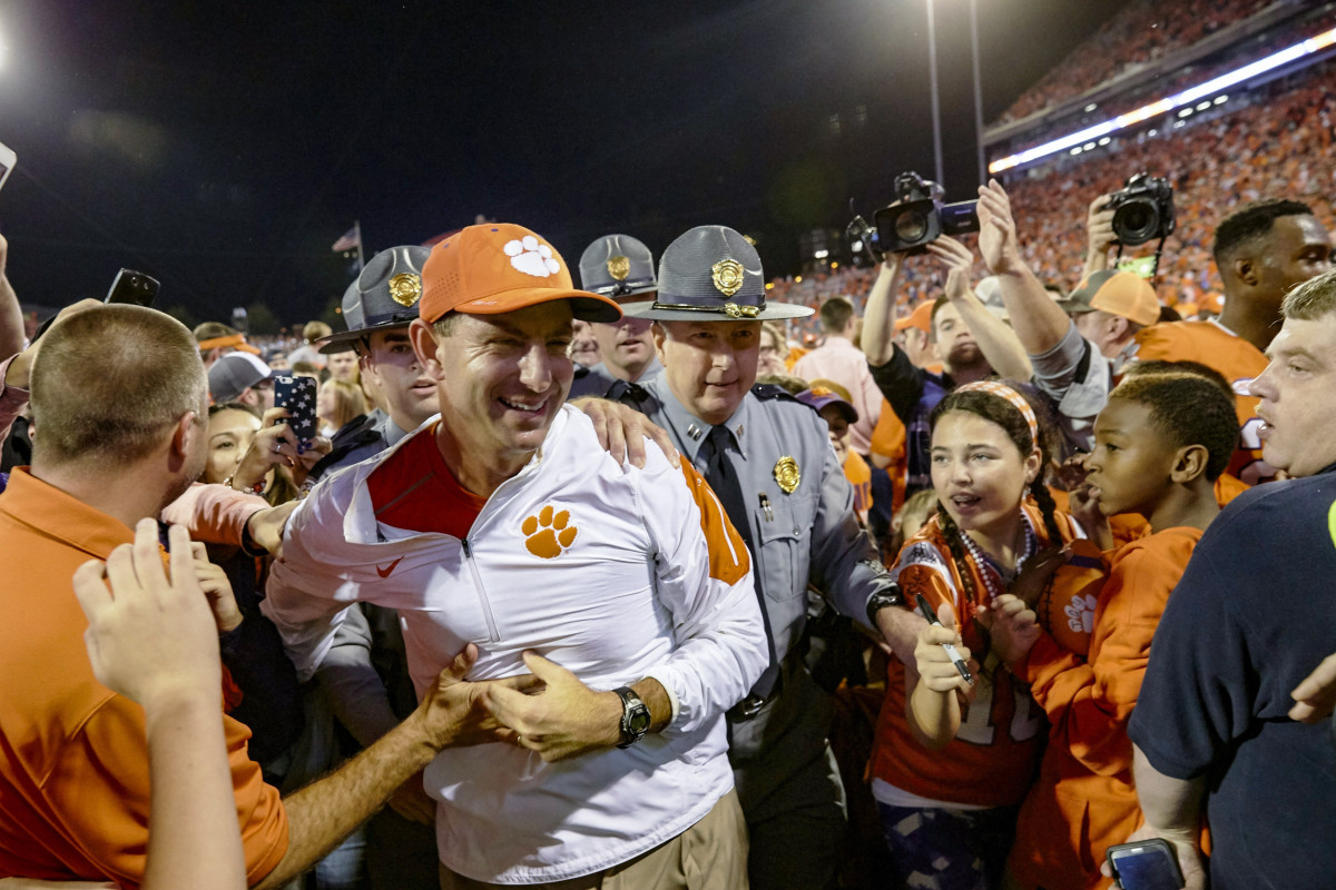 Security escort Clemson coach Dabo Swinney off the field.